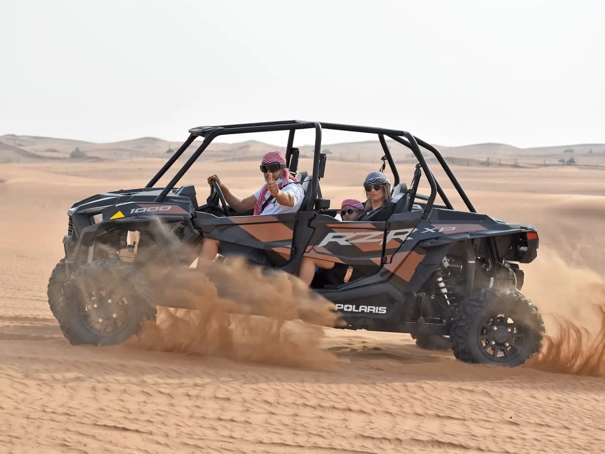 Vehicle crossing the desert dunes at sunset